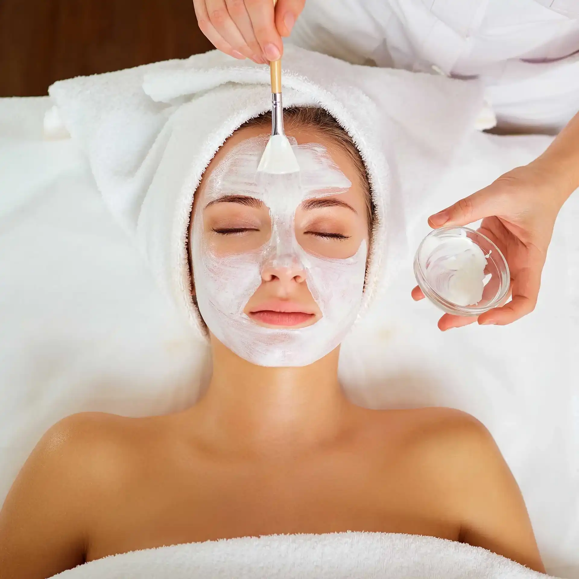 Woman receiving a relaxing facial mask treatment at a spa.